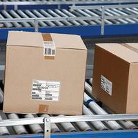 Étiquette d'expédition sur des cartons bruns, sur un tapis roulant dans la logistique.