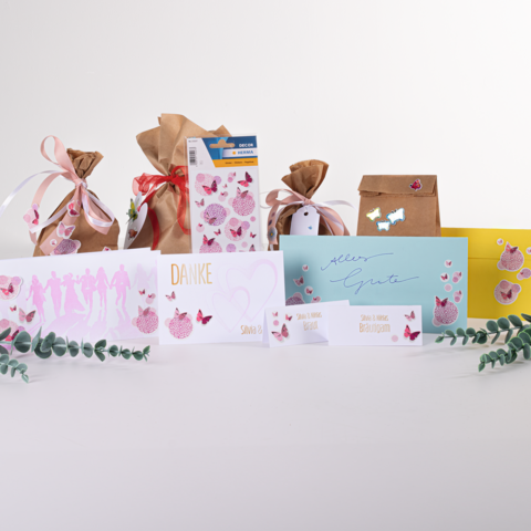 Text: "Des sacs-cadeaux et des cartes de différentes couleurs et designs, y compris une carte 'Merci' et une carte 'Tous mes vœux', décorées de papillons.
