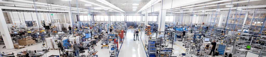 Une grande halle de fabrication moderne avec plusieurs postes de travail, des machines et des employés qui travaillent sur différents projets.