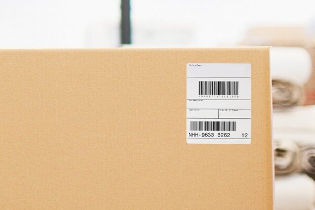 Étiquettes d'expédition HERMA et étiquettes de transport sur des cartons dans le domaine logistique, format paysage