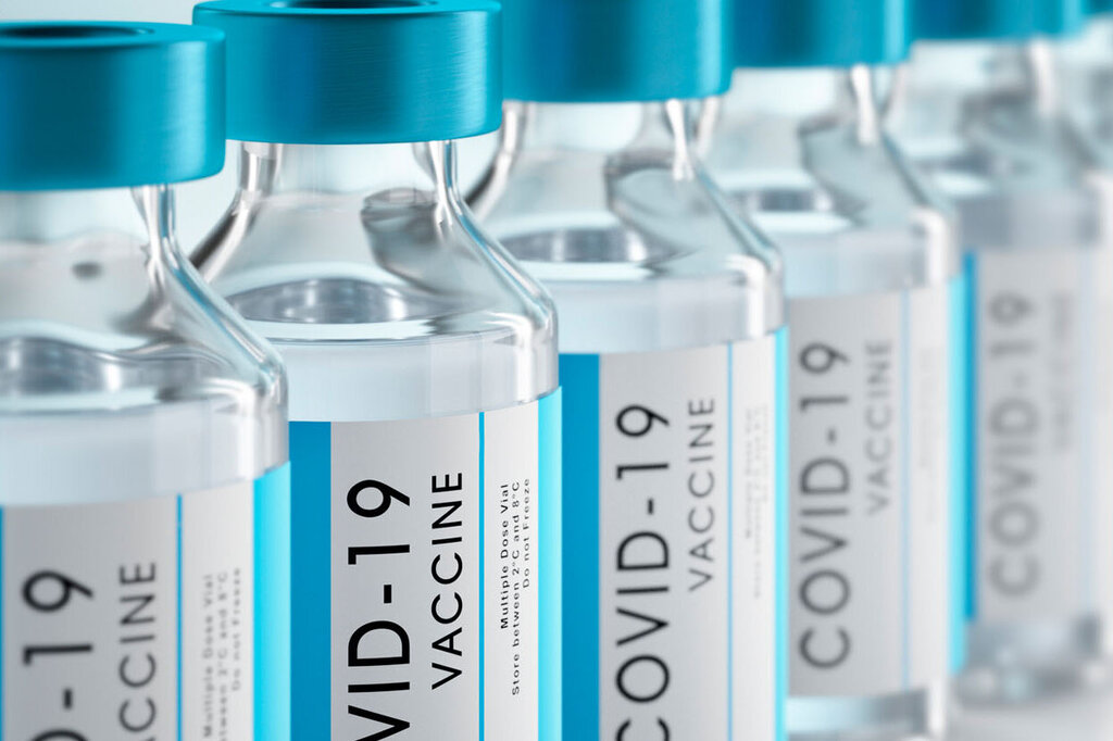 Une série de flacons de vaccin avec des bouchons bleus, étiquetés 'Vaccin COVID-19'.