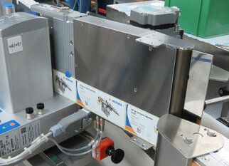 Une machine à étiqueter avec plusieurs rouleaux d'étiquettes et des éléments de commande, conçue pour des applications industrielles.
