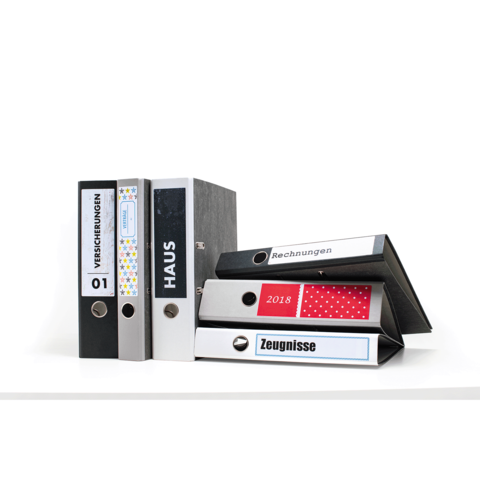 Eine Gruppe von Aktenordnern in verschiedenen Farben und Designs, beschriftet mit "Versicherungen", "Haus", "Rechnungen" und "Zeugnissen".