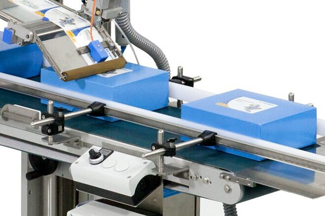 Une machine d'emballage avec des cartons bleus sur un tapis roulant, utilisée pour l'automatisation des processus d'emballage.