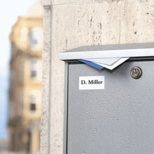 Briefkasten mit dem Namen "D. Miller" auf einer Wand, leicht feucht, mit Briefen, die aus dem oberen Schlitz herausragen.