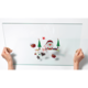 Eine transparente Glasplatte wird von zwei Händen gehalten, mit weihnachtlichen Motiven wie einem Schneemann, Geschenken und Tannenbäumen.