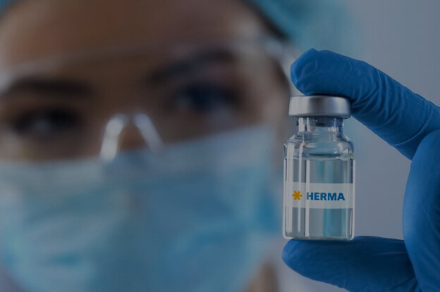 Une personne en tenue de protection tient une bouteille de vaccin étiquetée "Chine" dans la main.