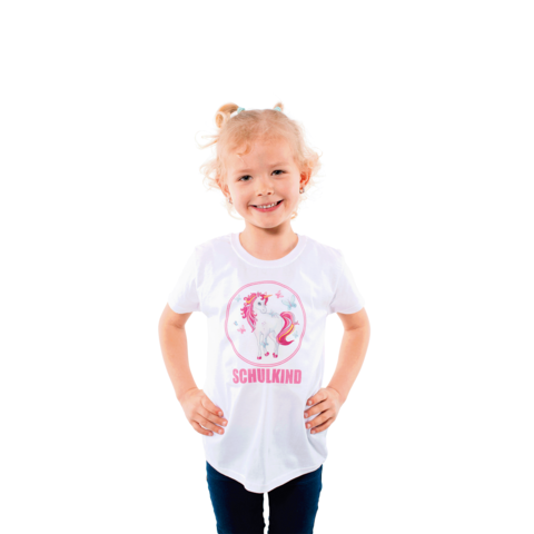 Ein lächelndes Kind mit lockigem Haar trägt ein weißes T-Shirt mit einem Einhorn und dem Text "SCHULKIND".