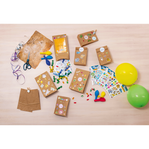 Bastelmaterialien auf einem Tisch, einschließlich Papiertüten, Aufklebern, Scheren, Ballons und bunten Perlen.