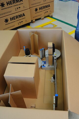 Un carton avec un étiqueteur et diverses emballages préparés pour des fins d'emballage.