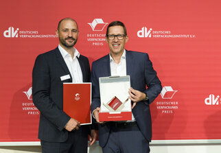 Deux hommes se tiennent côte à côte, tenant des récompenses dans leurs mains. En arrière-plan, on peut voir une bannière rouge avec le logo de l'Institut allemand de l'emballage.