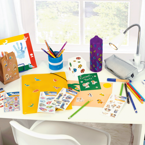 Bureau coloré décoré avec des fournitures de bricolage, y compris des stylos, des autocollants, un classeur et une lampe.