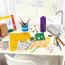 Bureau coloré décoré avec des fournitures de bricolage, y compris des stylos, des autocollants, un classeur et une lampe.