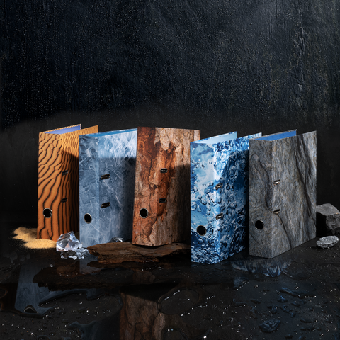 Farbenfrohe Ordner in verschiedenen Texturen stehen nebeneinander, darunter Holz-, Stein- und Wasseroptik.