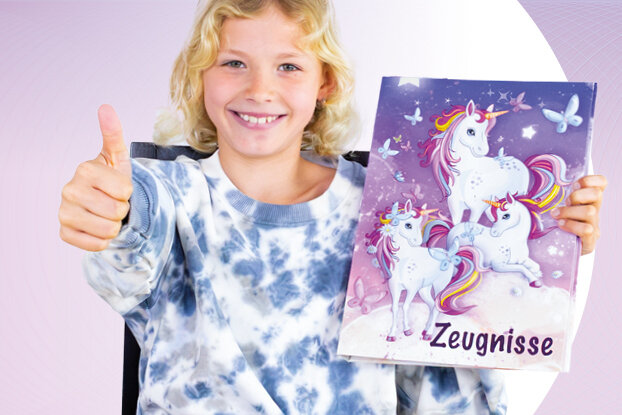 Un garçon montre un pouce en l'air et sourit, tout en tenant un classeur coloré avec un design de licorne et des pages vierges.
