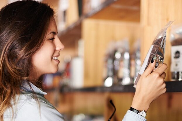 Femme devant une étagère de café, image pour l'étiquetage des aliments, format paysage